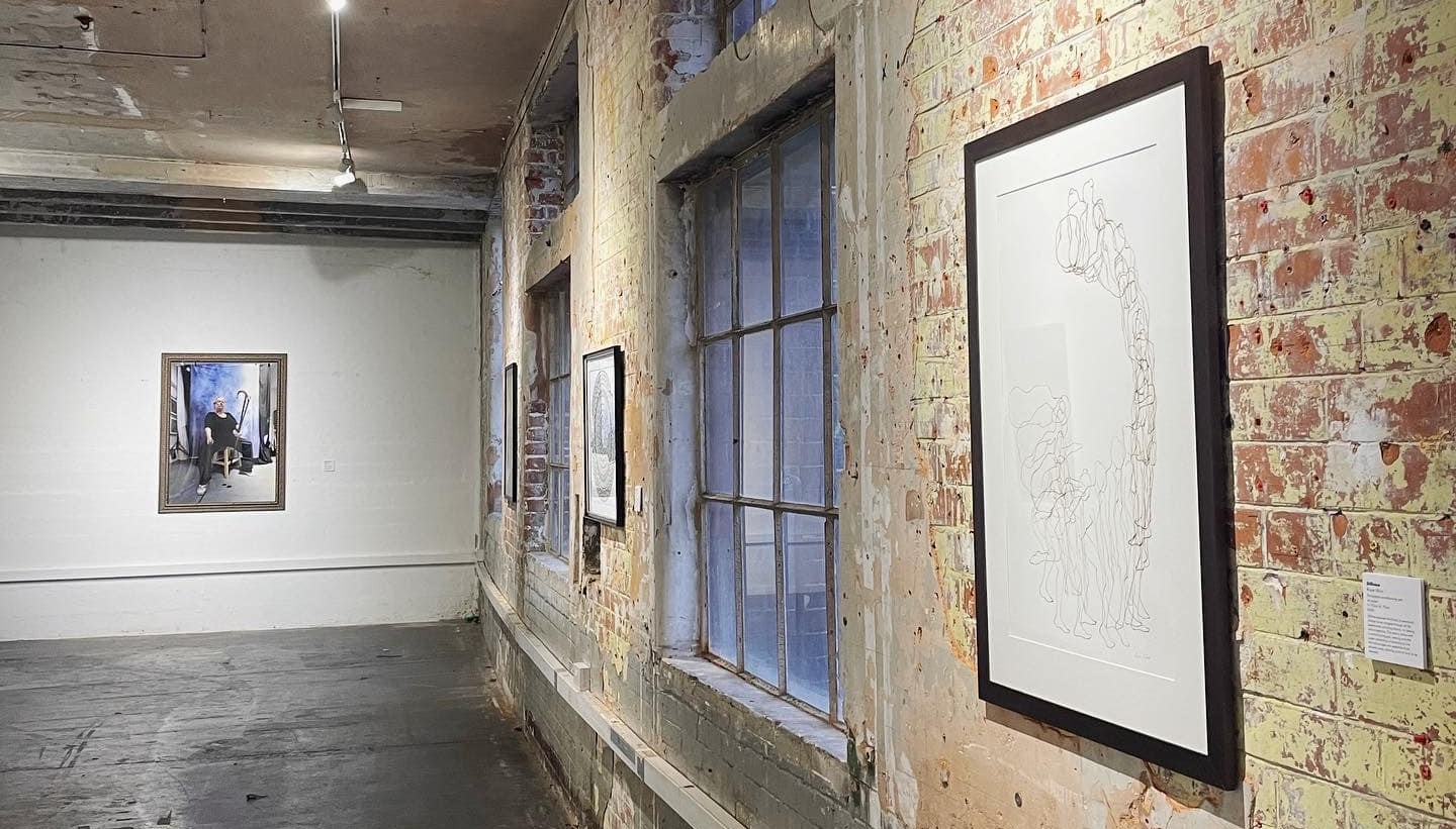 Different styles of artwork hanging on brick walls in a gallery